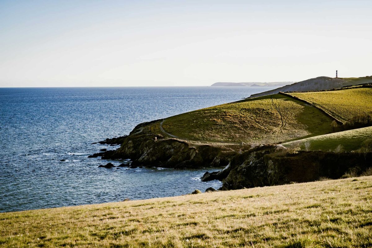 Sunset over St Catherine's Head, green field at the coast, UK