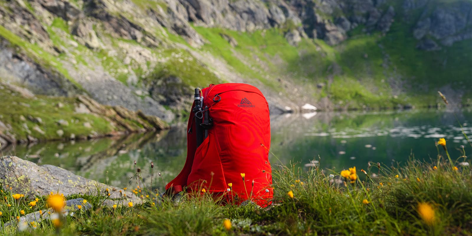 Gregory Kiro 24 sitting in the grass next to mountain lake